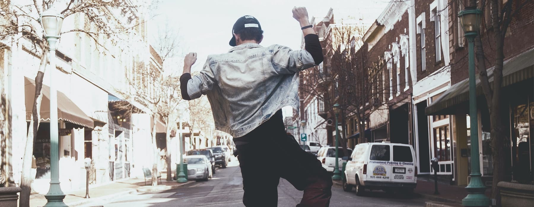 lifestyle image of a man jumping up in style in a neighborhood street